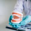 Dentist holding dentures in office room